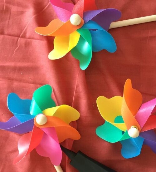 Mehrere bunte Windr&auml;dchen liegen auf einem roten Stoff.