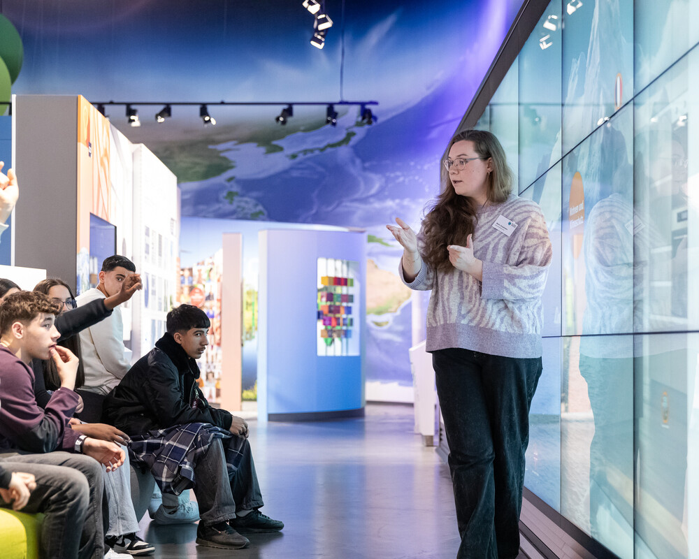 Besucherbetreuerin mit Schulklasse bei einer F&uuml;hrung durch die Ausstellung.