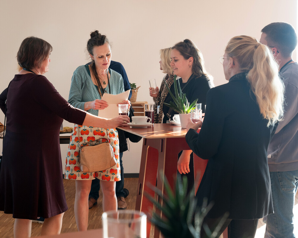 Ein Arbeitsteam steht um einen Tisch und redet miteinander